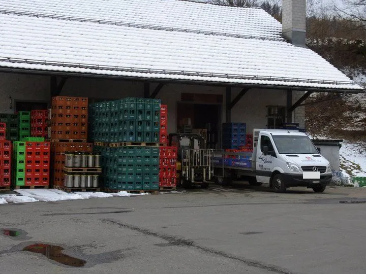 Pritschenwagen und Stapler beim Beladen vor dem Lager, Harasse und Fässer bereit