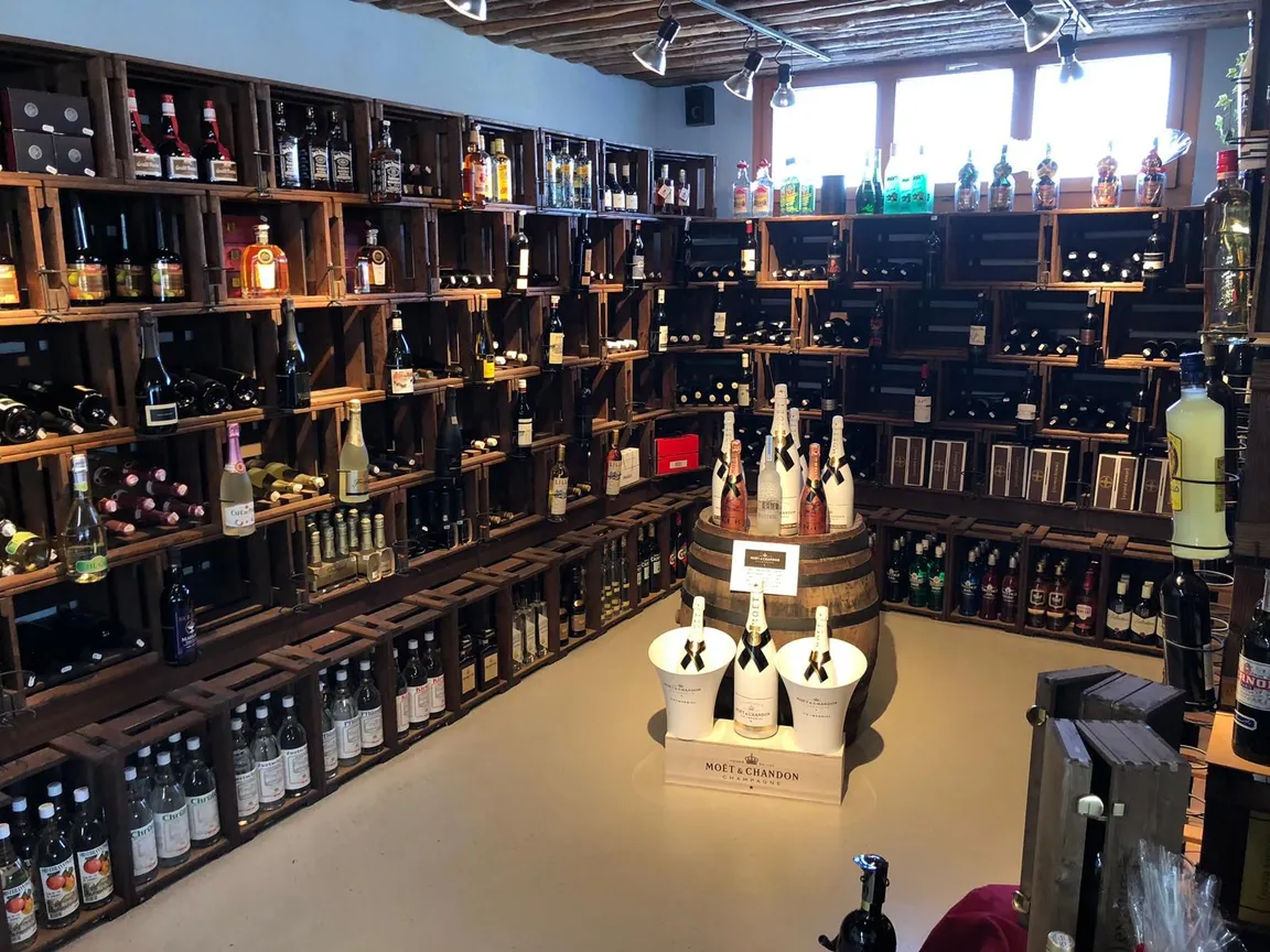Weinabteilung mit Holzfass und aufgebauten Flaschen im Abholmarkt von Egli Getränke
