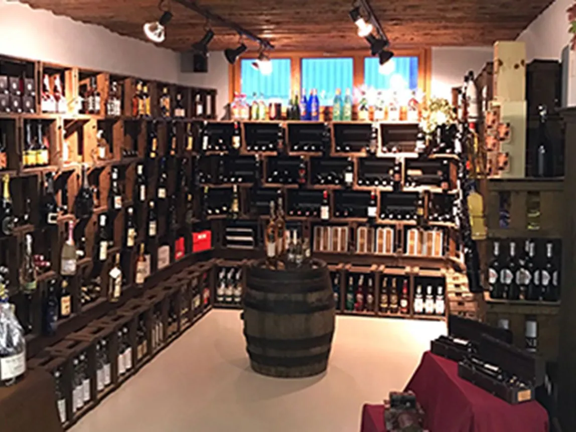 Übersicht über die Weinabteilung mit Regalen aus Holzkisten und einem Fass